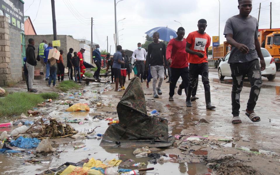 People walk down a water-logged road in Lusaka, Zambia