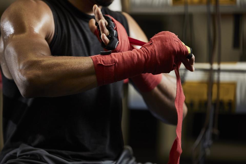 midsection of male boxer wrapping protective bandage on hand