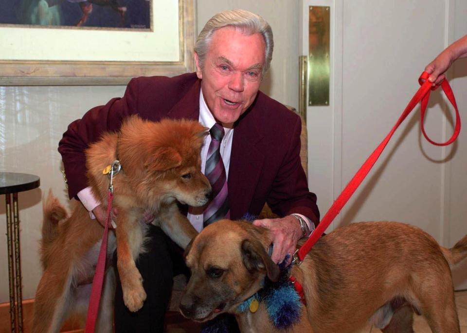 In this undated file photo, legendary meteorologist Dick Goddard hangs out with Happy, a Chow mix, and Murphy, a shepherd mix, from the Humane Society of Summit County at the "Shout it from the Wooftops" fundraiser.