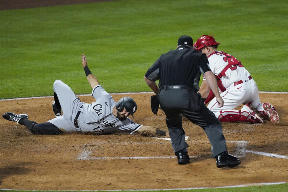 Chicago White Sox's Adam Eaton (12) avoids a tag attempt by Los Angeles Angels catcher Max Stassi (33) for a score during the fourth inning of an MLB baseball game Friday, April 2, 2021, in Anaheim, Calif. (AP Photo/Ashley Landis)