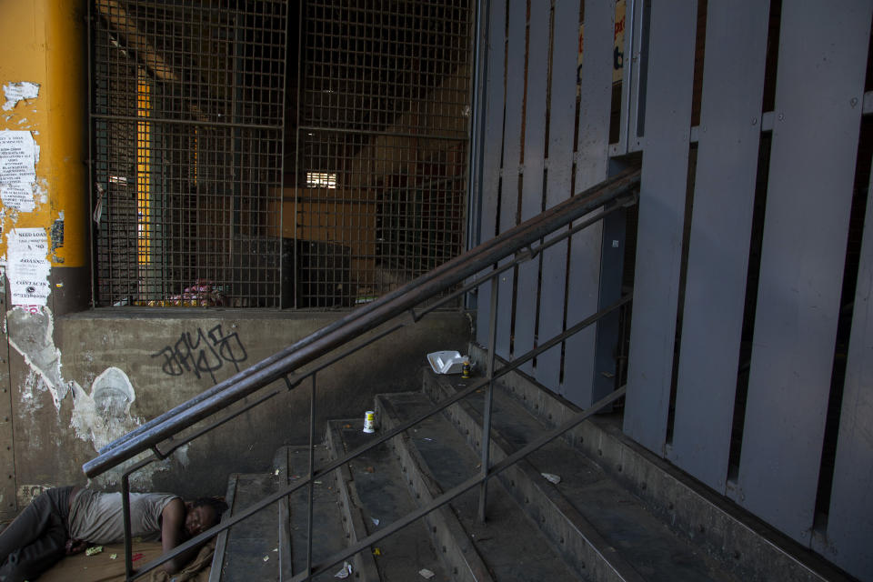 A homeless man sleeps on sidewalk in downtown Johannesburg, South Africa, Monday, May 11, 2020. (AP Photo/Themba Hadebe)