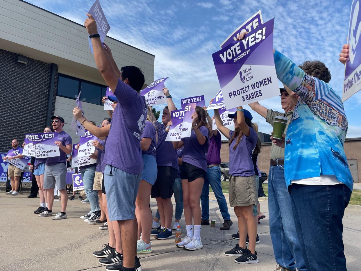 Supporters of Amendment 2 hold signs reading: Vote yes on August 2nd, Value Them Both, protect women & babies.