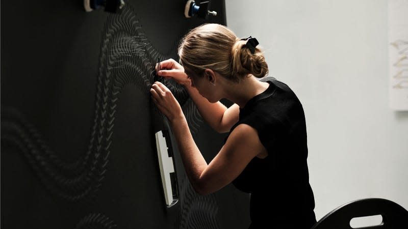 A photo of a craftsperson attaching 162 glass petals to the roof lining. 