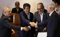 From left, Australian Prime Minister Scott Morrison, Japan Prime Minister Shinzo Abe, Papua New Guinea Prime Minister Peter O'Neill and U.S. Vice President Mike Pence shake hands during the Leaders Electrification Project meeting as part of the APEC 2018 at Port Moresby, Papua New Guinea on Sunday, Nov. 18, 2018. In a statement issued to media, Papua New Guinea has invited Australia, Japan, New Zealand and the United States to work together to support its enhanced connectivity and the goal of connecting 70% of its population to electricity by 2030. Currently only about 13% of Papua New Guinea's population have reliable access to electricity. (AP Photo/Aaron Favila)