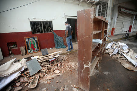 A resident stands near an image of the Virgin of Guadalupe and debris after an earthquake struck the southern coast of Mexico late on Thursday, in Juchitan, Mexico, September 10, 2017. REUTERS/Edgard Garrido