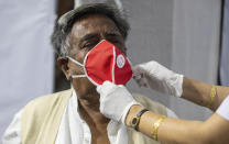 A health worker adjusts the face mask of an elderly person before administering COVISHIELD vaccine at the Guwahati Medical College hospital in Gauhati, India, Monday, March 1, 2021. India is expanding its COVID-19 vaccination drive beyond health care and front-line workers, offering the shots to older people and those with medical conditions that put them at risk. (AP Photo/Anupam Nath)