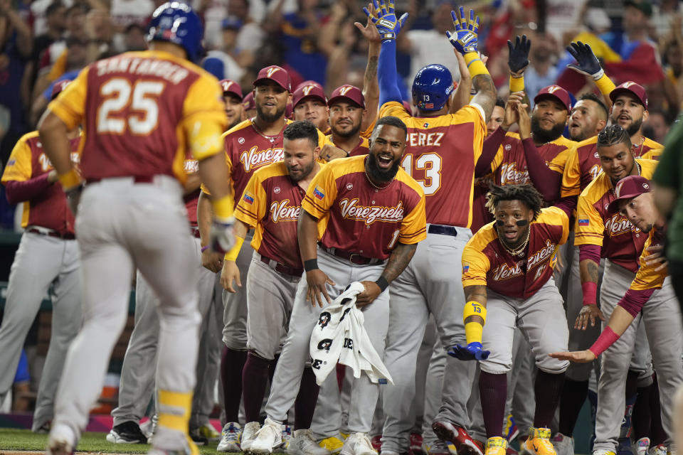 Los jugadores de Venezuela reciben a Anthony Santander (25) tras conectar un jonrón en el primer inning ante Puerto Rico en el Clásico Mundial de béisbol, el domingo 12 de marzo de 2023 en Miami. (AP Foto/Wilfredo Lee)