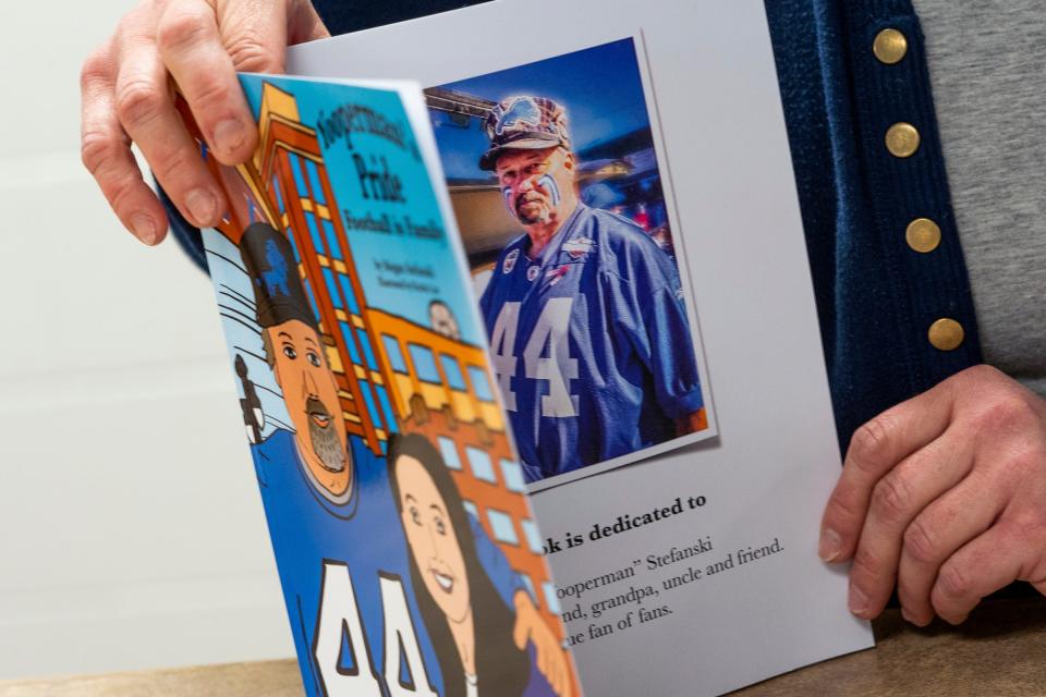 Detroit Lions superfan Megan "Yoopergirl" Stefanski shows a page from the children's book she wrote about traveling to the Detroit Lions games with her father, Donnie, on Wednesday, Aug. 30, 2023, at the DeTour Public Library, where she works as a school librarian.