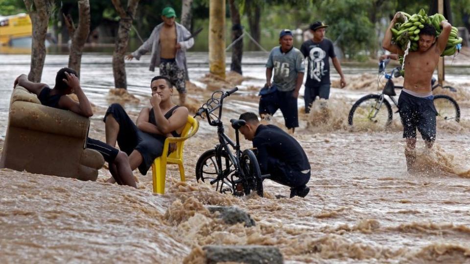 Personas en en medio una calle inundada