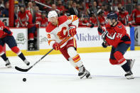 Calgary Flames center Trevor Lewis (22) chases the puck past Washington Capitals center Connor McMichael (24) during the second period of an NHL hockey game, Saturday, Oct. 23, 2021, in Washington. (AP Photo/Nick Wass)