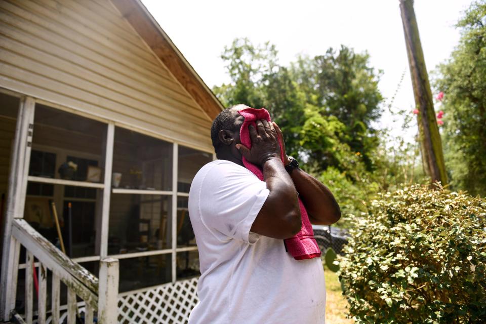 Henry Thomas uses a towel to wipe tears and sweat from his face in front of his grandmother's house, where he was born and raised, in Walterboro, S.C., on Saturday, July 1, 2023. This is Henry's first visit back to Walterboro since being incarcerated, and the first time seeing many of his family members and friends since his sentence.