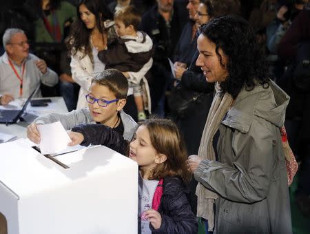 Children help put in their mother's ballot as she votes in a symbolic independence vote in Barcelona, November 9, 2014. REUTERS/Paul Hanna