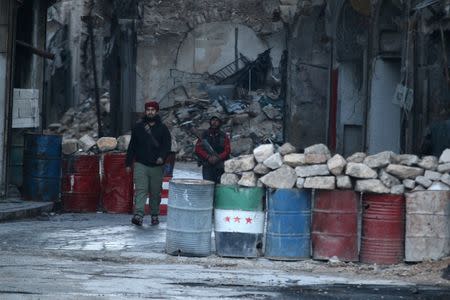 A rebel fighter stands with his weapon near damaged buildings, and barricades with a Free Syrian Army flag drawn(C), in rebel-held besieged old Aleppo, Syria December 2, 2016. REUTERS/Abdalrhman Ismail