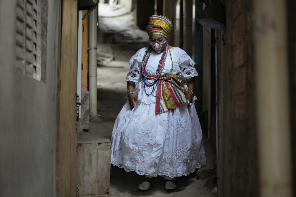 Street food vendor Mila Veloso walks through an alley in the Paraisopolis favela, during the community's centennial celebration, in Sao Paulo, Brazil, Thursday, Sept. 16, 2021. One of the largest favela's in Brazil, home to tens of thousands of residents in the country's largest and wealthiest city, Paraisopolis is grappling with crime and a pandemic that have challenged daily life for many who live there, but organizers say its people have built a vibrant community and are launching a 10-day celebration of its achievements. (AP Photo/Andre Penner)