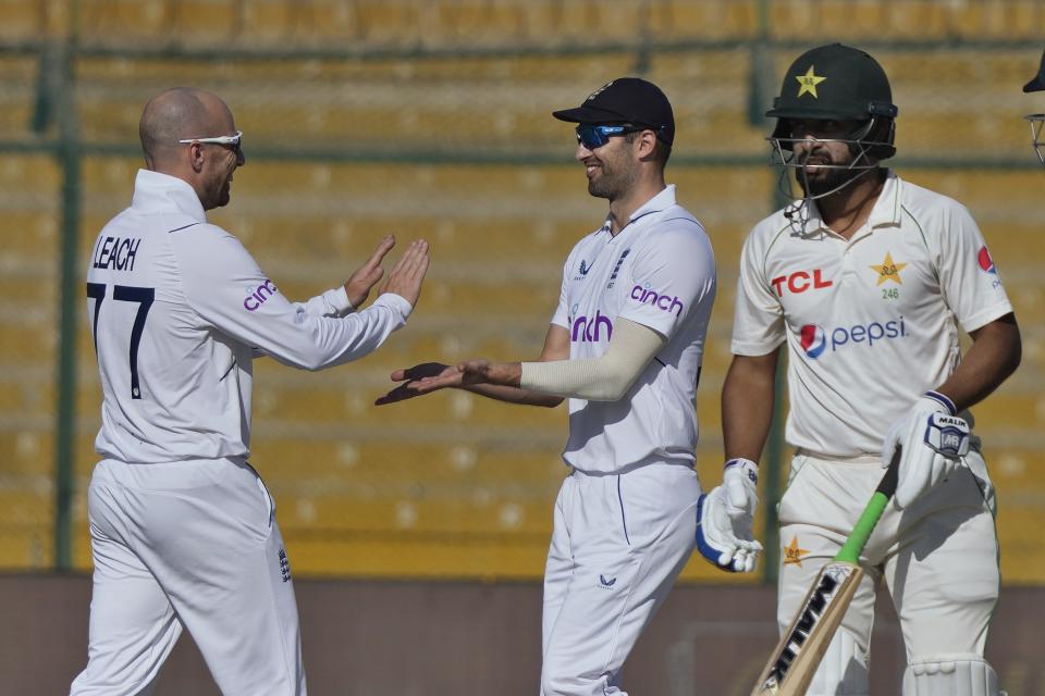 England's Jack Leach, left, celebrates with teammate after taking the wicket of Pakistan's Abdullah Shafique, right, during the first day of third test cricket match between England and Pakistan, in Karachi, Pakistan, Saturday, Dec. 17, 2022. (AP Photo/Fareed Khan)