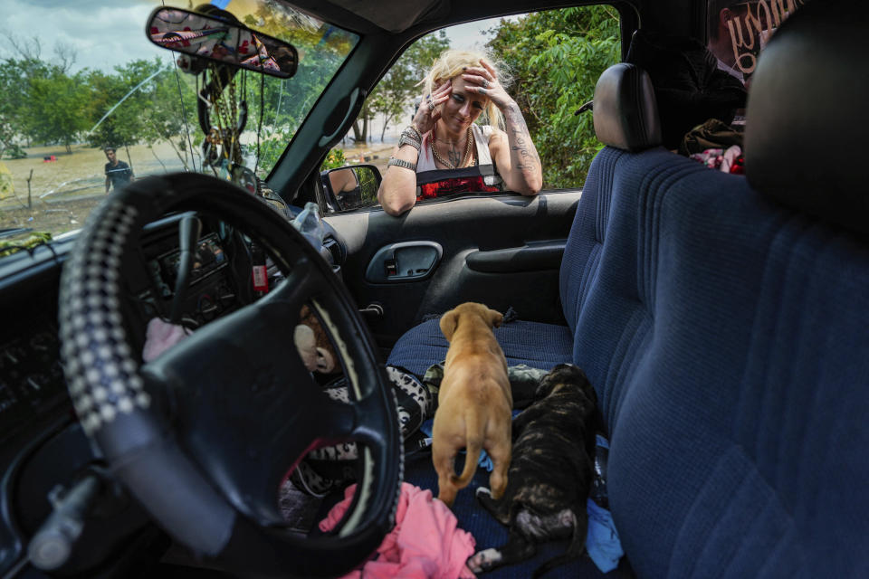 A woman, who only gave her name as Lisamarie, checks on two of her puppies after her neighborhood was evacuated due to severe flooding on Saturday, May 4, 2024, in Channelview, Texas. (Raquel Natalicchio/Houston Chronicle via AP)