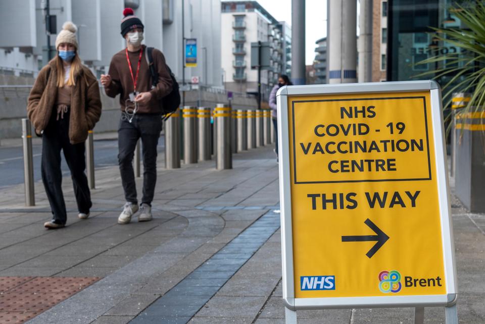 A sign for a COVID-19 vaccination center in London, with an arrow and the words: This Way.