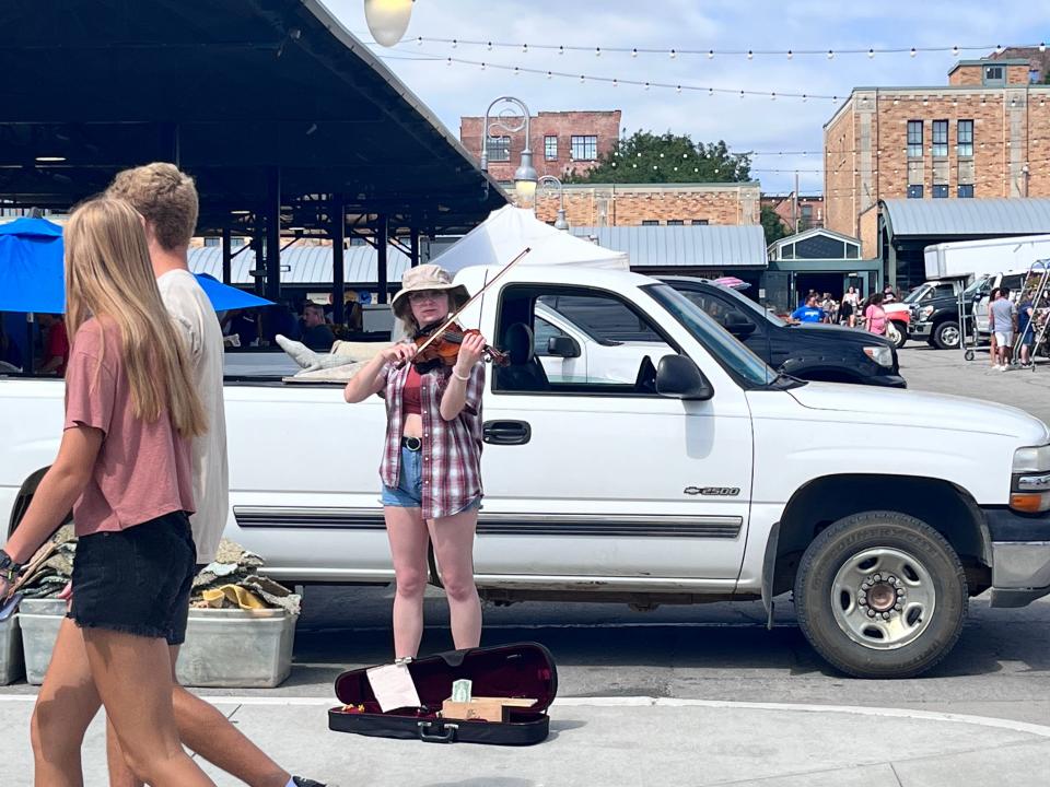 person playing the violin on the streets of kansas city in front of a white pickup truck