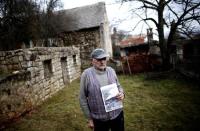 The grandson of Gavrilo Princip's brother, Miljkan Princip poses with a photo of Princip's house in front it in Bosansko Grahovo, January 31, 2014. REUTERS/Dado Ruvic