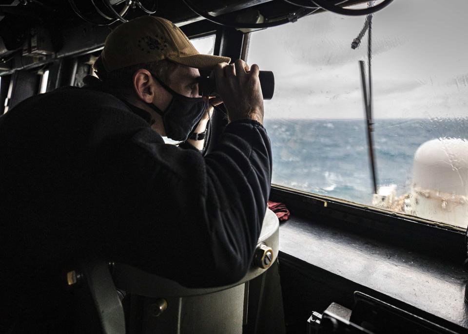 In this photo provided by U.S. Navy, Ensign Grayson Sigler, from Corpus Christi, TX., scans the horizon while standing watch in the pilot house as guided-missile destroyer USS John S. McCain conducts routine underway operations in support of stability and security for a free and open Indo-Pacific, at the Taiwan Strait, Wednesday, Dec. 30, 2020. China accused the U.S. of staging a show of force by sailing two Navy warships through the Taiwan Strait on Thursday morning. The Navy said the Arleigh Burke-class guided missile destroyers USS John S. McCain and USS Curtis Wilbur “conducted a routine Taiwan Strait transit” in accordance with international law. (Mass Communication Specialist 2nd Class Markus Castaneda/U.S. Navy via AP)