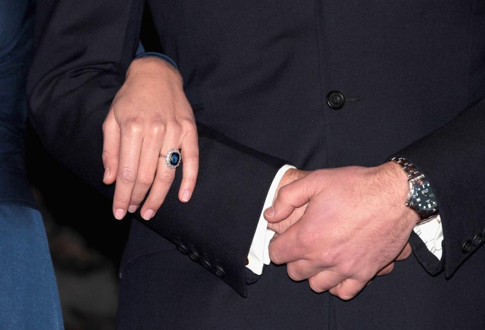 a large sapphire ring surrounded by diamonds is worn on a hand