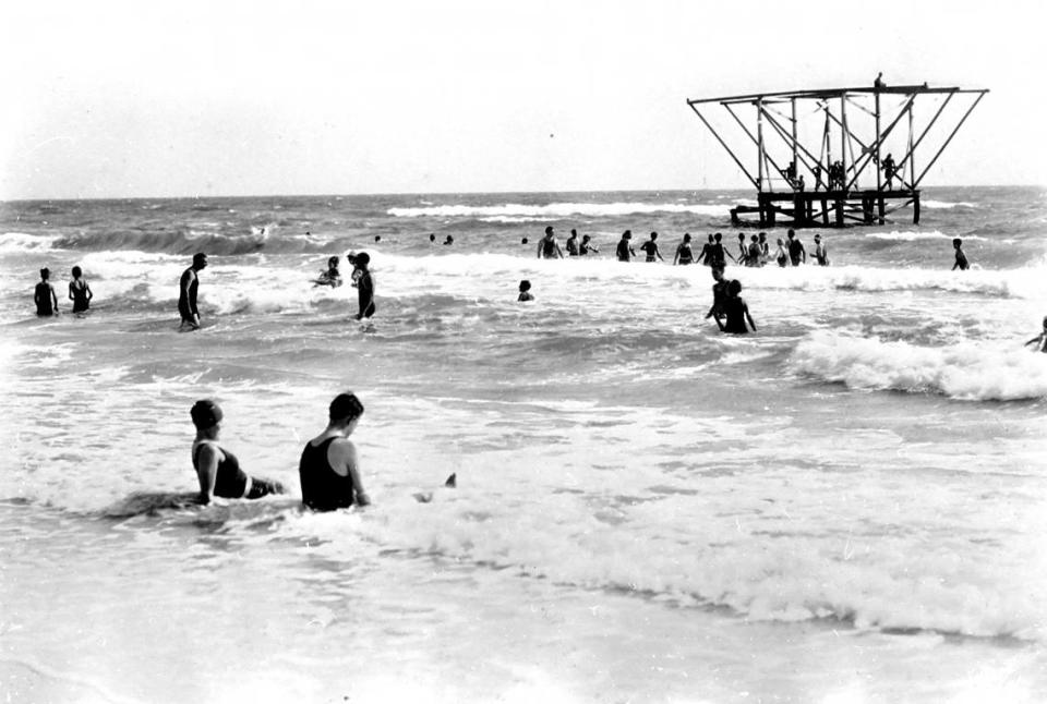 Visitors and residents cooling off in the water at the Bradenton Beach in the 1920s. A structure in the water offers a diving board for use.