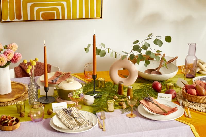 Angled view of a set colorful holiday tablescape with flowers and candles.