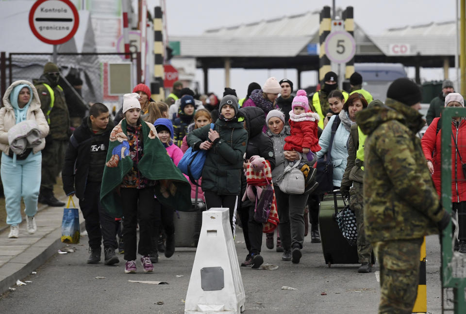People carry their belongings at the Ukrainian-Polish border crossing in Korczowa, Poland, Saturday, March 5, 2022. (Olivier Douliery, Pool Photo via AP)