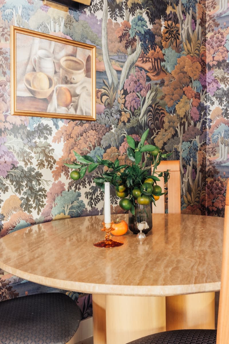 dining room with trees wallpaper and wood round dining table