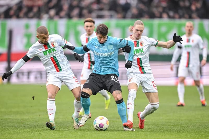 Augsburg's Niklas Dorsch (L) and Leverkusen's Adam Hlozek (C) and Augsburg's Fredrik Jensen (R) battle for the ball during the German Bundesliga soccer match between FC Augsburg and Bayer Leverkusen at the WWK Arena. Harry Langer/dpa