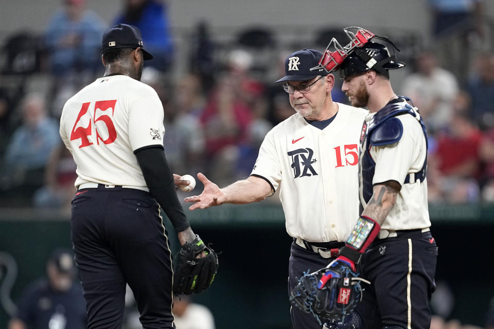 Texas Rangers relief pitcher Aroldis Chapman (45) turns the ball over to manager Bruce Bochy (15) as catcher Jonah Heim, right, looks on in the 10th inning of a baseball game against the Minnesota Twins, Saturday, Sept. 2, 2023, in Arlington, Texas. (AP Photo/Tony Gutierrez)