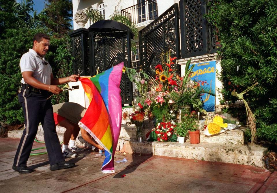 En esta foto de archivo del 22 de julio de 1997, un guardia de seguridad privado armado retira una bandera dejada por un admirador frente al monumento público improvisado para Gianni Verace, el diseñador de moda internacionalmente conocido que fue asesinado en las escaleras de su mansión una semana antes por Andrew Cunanan.