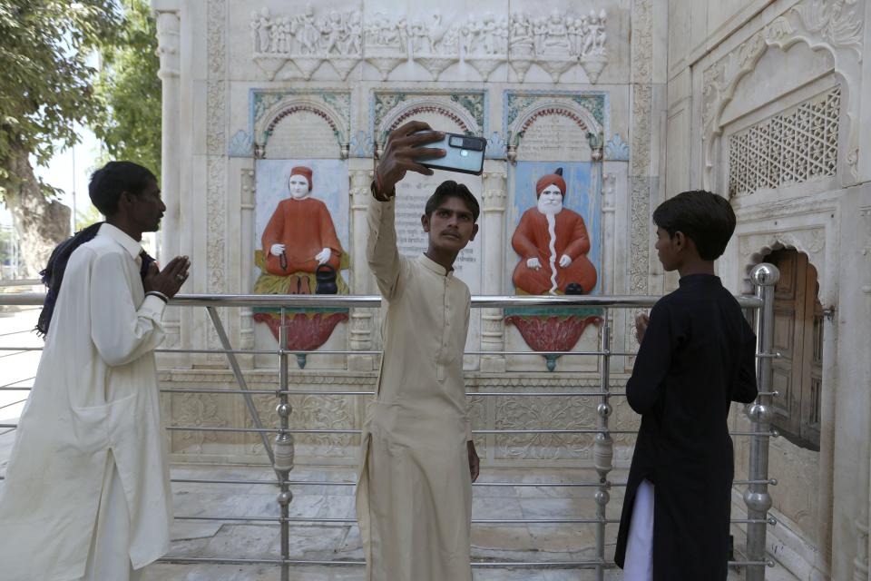 A teenager from Pakistani Hindu community takes selfie with his phone while he with others visit at the Sadhu Bela temple, located in an island on the Indus River, in Sukkur, Pakistan, Wednesday, Oct. 26, 2022. On the banks of the Indus River, which flows through Pakistan and into its southern Sindh province, Hindus wait for brightly colored boats to ferry them to an island that has housed Sadhu Bela temple for almost 200 years. The island was gifted to the Hindu community by wealthy Muslim landlords in Sindh, an unthinkable act in modern-day Pakistan. (AP Photo/Fareed Khan)