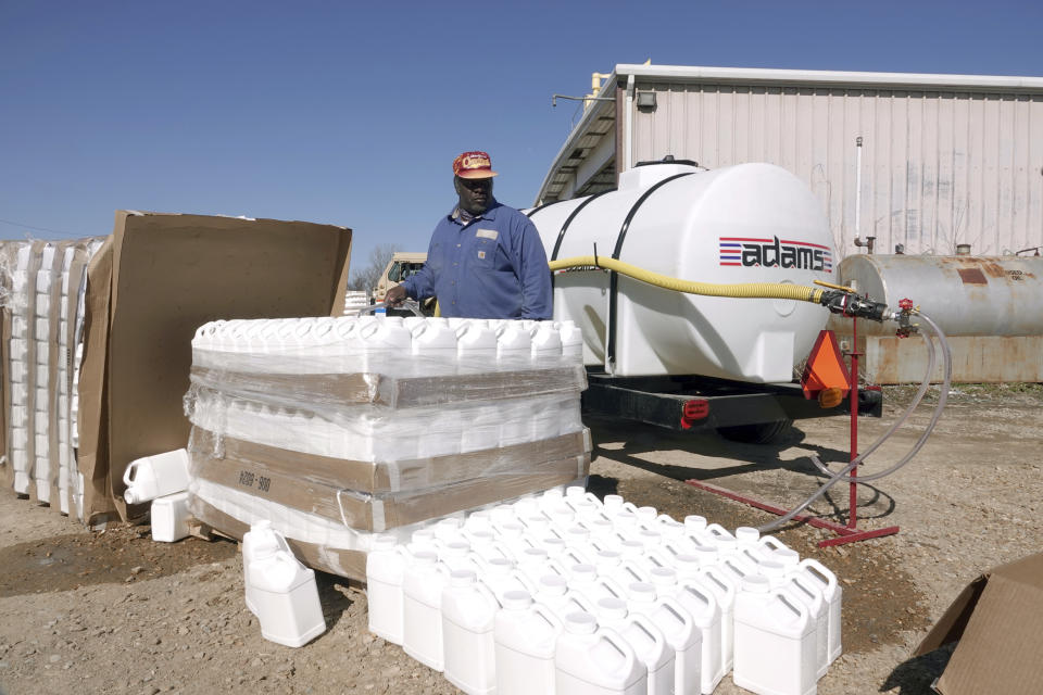 George Jackson fills up one gallon water jugs, while other Phillips County employees distribute water for people without water Tuesday, Jan. 30, 2024, in Helena, Arkansas. Parts of the east Arkansas town has been without water for two weeks after the state was hit by below freezing temperatures, and residents have been lining up for jugs of water and a truck of mobile showers dispatched to the community. (AP Photo/Karen Pulfer Focht)