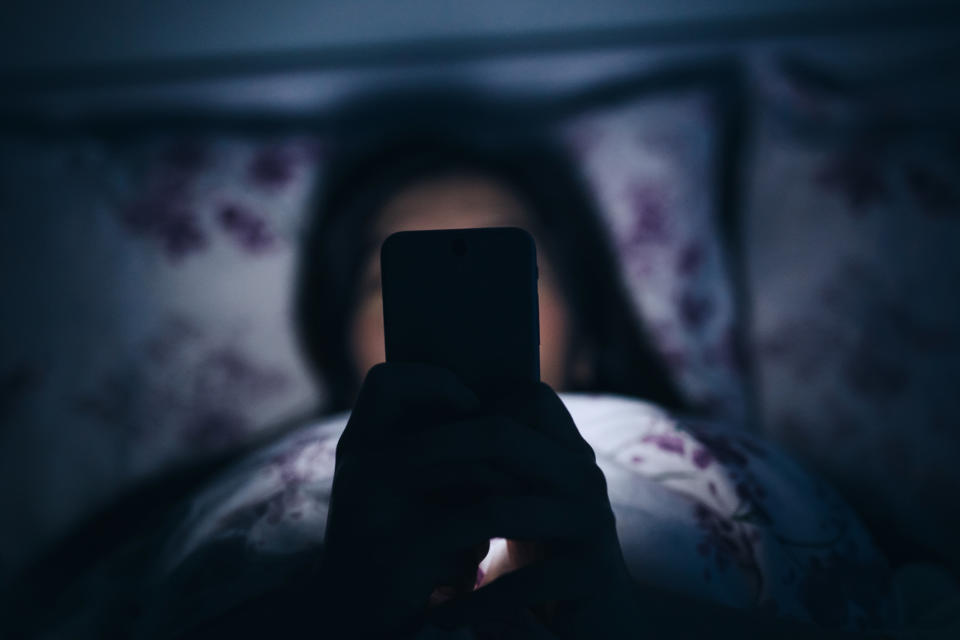 A person in bed looking at smartphone screen in the dark