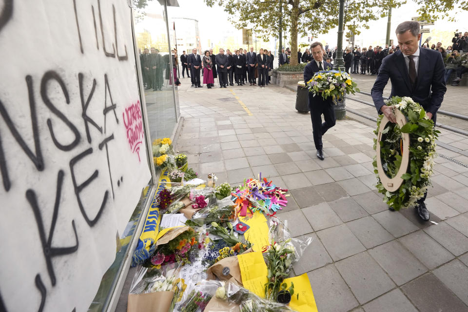 Sweden's Prime Minister Ulf Kristersson, center, and Belgium's Prime Minister Alexander De Croo, right, carry floral tributes during a commemoration for the victims of a shooting in the center of Brussels, Wednesday, Oct. 18, 2023. Police in Belgium on Tuesday shot dead a suspected Tunisian extremist accused of killing two Swedish soccer fans in a brazen attack on a Brussels street. (AP Photo/Martin Meissner)