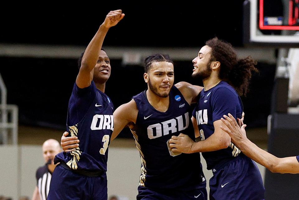 Max Abmas, Kevin Obanor, and Kareem Thompson of the Oral Roberts Golden Eagles celebrate after defeating the Florida Gators.