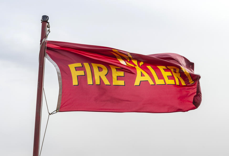 A fire alert flag flies in strong Santa Ana winds at the intersection of Silverado Canyon Road and Santiago Canyon Road in Silverado, Calif., early on Tuesday afternoon, Jan. 19, 2021, as winds picked up throughout Orange County and Southern California. (Mark Rightmire/The Orange County Register/SCNG via AP)