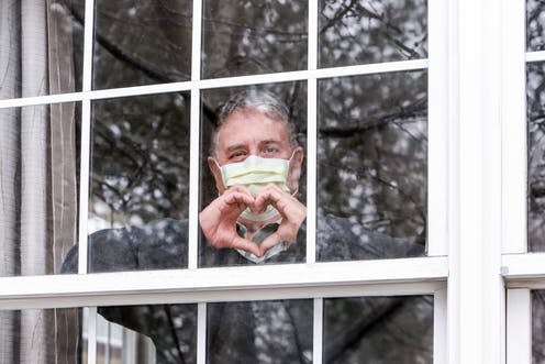 <span class="caption">The "tend and befriend" stress response encourage us to connect with people to reduce anxiety and stress. </span> <span class="attribution"><a class="link " href="https://www.shutterstock.com/image-photo/man-wearing-mask-making-heart-symbol-1681748269" rel="nofollow noopener" target="_blank" data-ylk="slk:Suzanne Tucker/ Shutterstock;elm:context_link;itc:0;sec:content-canvas">Suzanne Tucker/ Shutterstock</a></span>