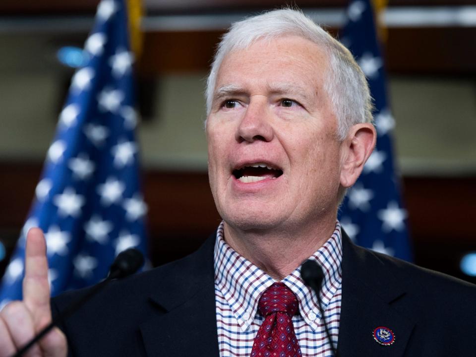 Republican Rep. Mo Brooks of Alabama, his right index finger raised, addressed a Capitol Hill press conference while standing against a backdrop of several American flags.