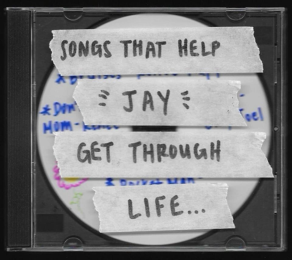 CD case labeled "SONGS THAT HELP GET THROUGH LIFE" with a name written in the center, surrounded by hearts