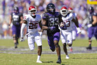 FILE - TCU running back Kendre Miller (33) breaks through the Oklahoma defense during an NCAA football game on Saturday, Oct. 1, 2022, in Fort Worth, Texas. The body types are certainly much different for TCU's Kendre Miller and Kansas State's 5-foot-6 dynamo Deuce Vaughn. And yet the running backs that will be featured in the Big 12 championship game look pretty similar in what they do on the field. (AP Photo/Brandon Wade, File)