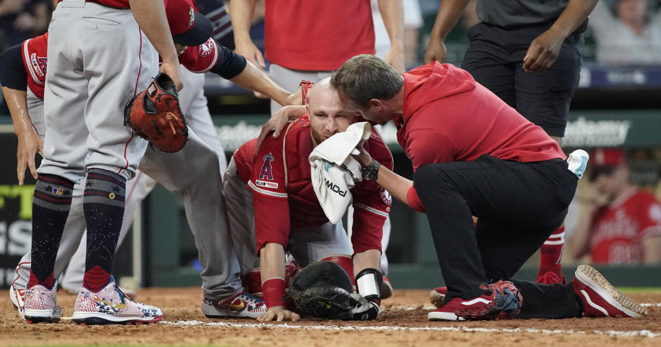 Los Angeles Angels' Jonathan Lucroy, center, is helped by medical personnel after colliding with Houston Astros' Jake Marisnick during the eighth inning of a baseball game Sunday, July 7, 2019, in Houston. (AP Photo/David J. Phillip)