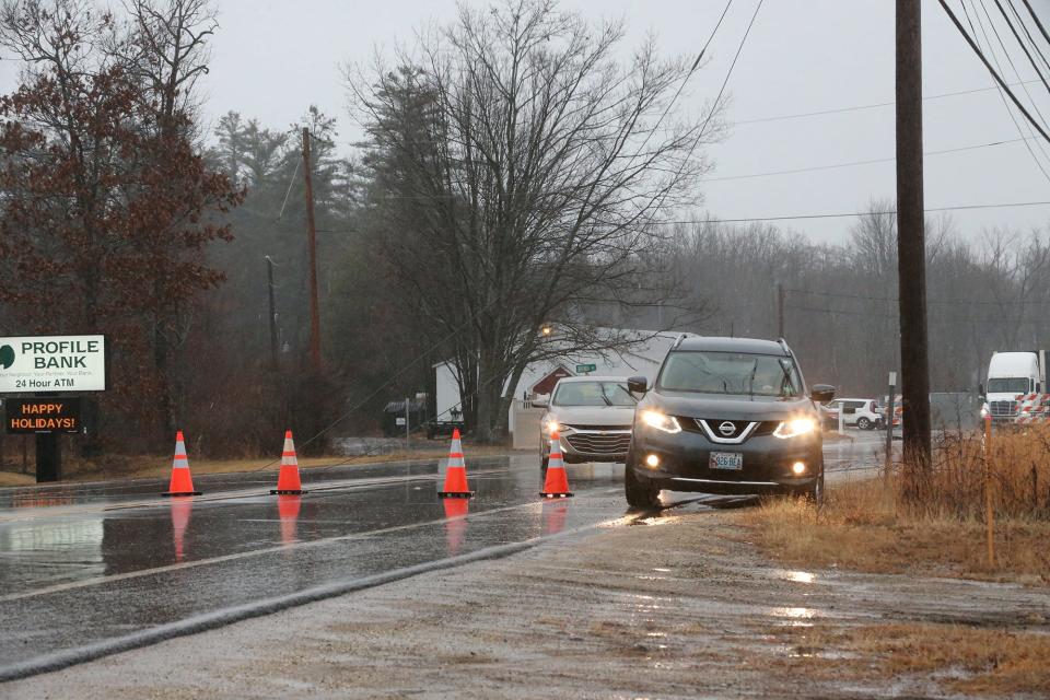 Vehicles make their way around downed power lines on Route 108 in Somersworth due to a storm with rain and high winds Monday, Dec. 18, 2023.