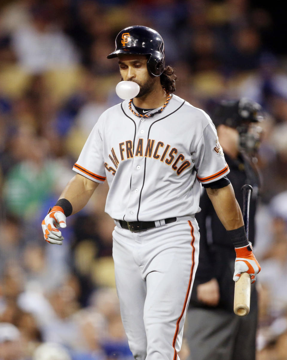 San Francisco Giants' Angel Pagan blows a bubble and walks back to the dugout after striking out looking against the Los Angeles Dodgers during the third inning of a baseball game, Friday, May 9, 2014, in Los Angeles. (AP Photo/Danny Moloshok)