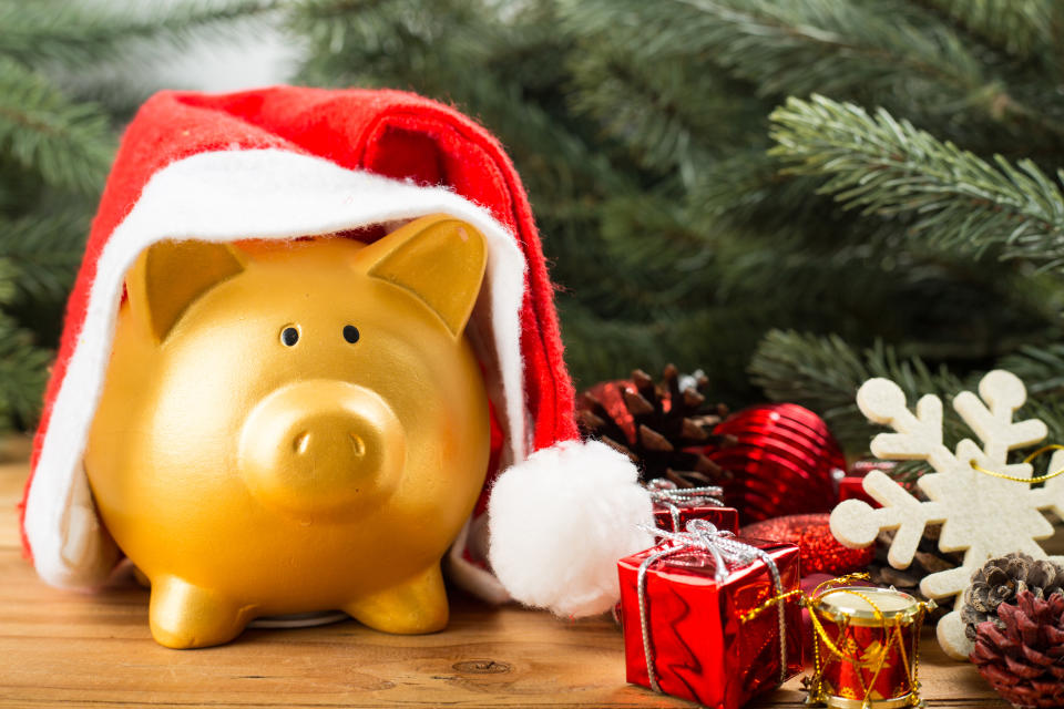 Golden Piggy bank with Santa hat under the Christmas tree.