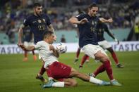 Denmark's Alexander Bah, center, competes for the ball with FFrance's Theo Hernandez, left and his teammate Adrien Rabiot during the World Cup group D soccer match between France and Denmark, at the Stadium 974 in Doha, Qatar, Saturday, Nov. 26, 2022. (AP Photo/Christophe Ena)