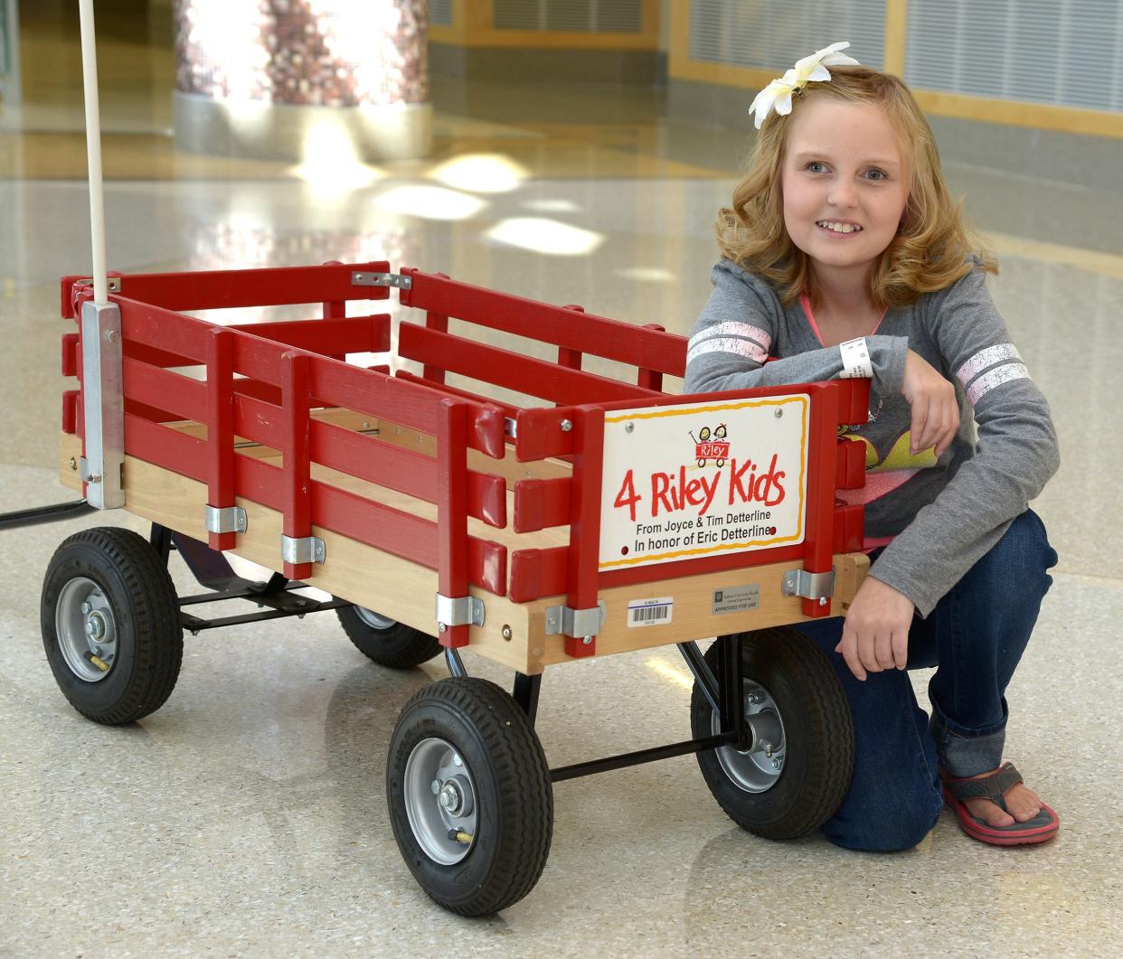 Emma Stumpf of Greenwood poses next to a Little Red Wagon, used to transport kids around Riley Hospital for Children in Indianapolis. In December, Charles Elementary School students raised enough to purchase a wagon, making Charles a Riley Miracle School.