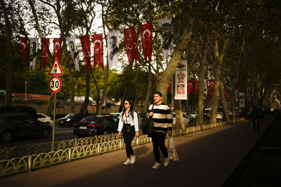 A couple walks in a street decorated with Turkish flags and pictures of Mustafa Kemal Ataturk, ahead of the 100 year anniversary of the modern Turkey, in Istanbul, Wednesday, Oct. 25, 2023. The Turkish Republic, founded from the ruins of the Ottoman Empire by the national independence hero Mustafa Kemal Ataturk, turns 100 on Oct. 29. Ataturk established a Western-facing secular republic modeled on the great powers of the time, ushering in radical reforms that abolished the caliphate, replaced the Arabic script with the Roman alphabet, gave women the vote and adopted European laws and codes. (AP Photo/Emrah Gurel)