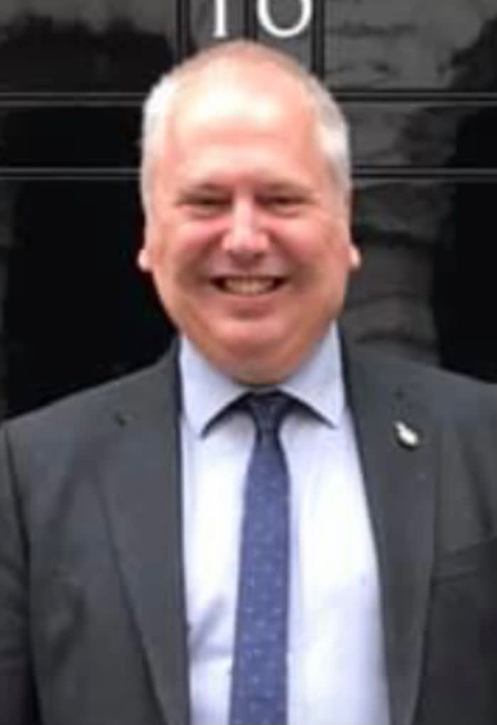 Man wearing a suit smiles while standing outside 10 Downing Street